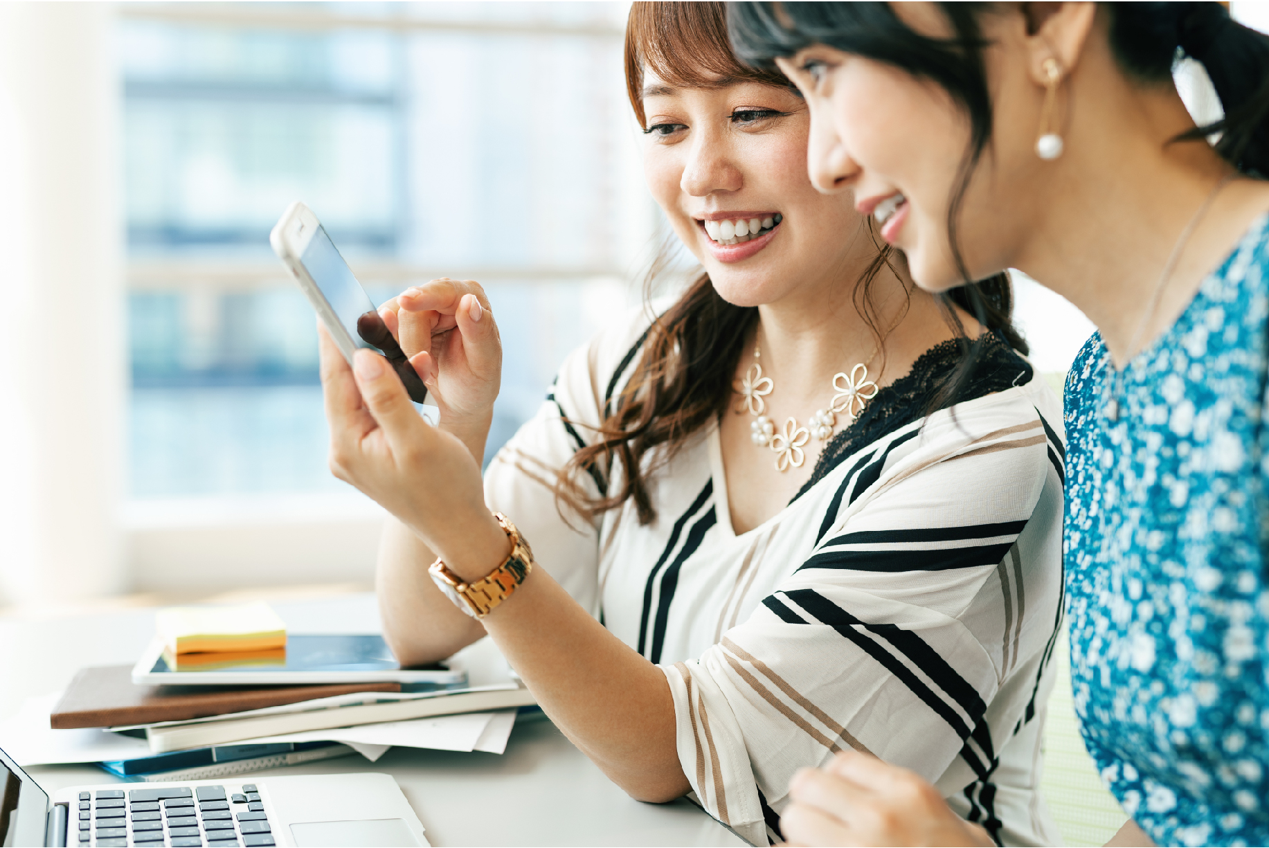 スマホを見て話し合う女性2人組の写真